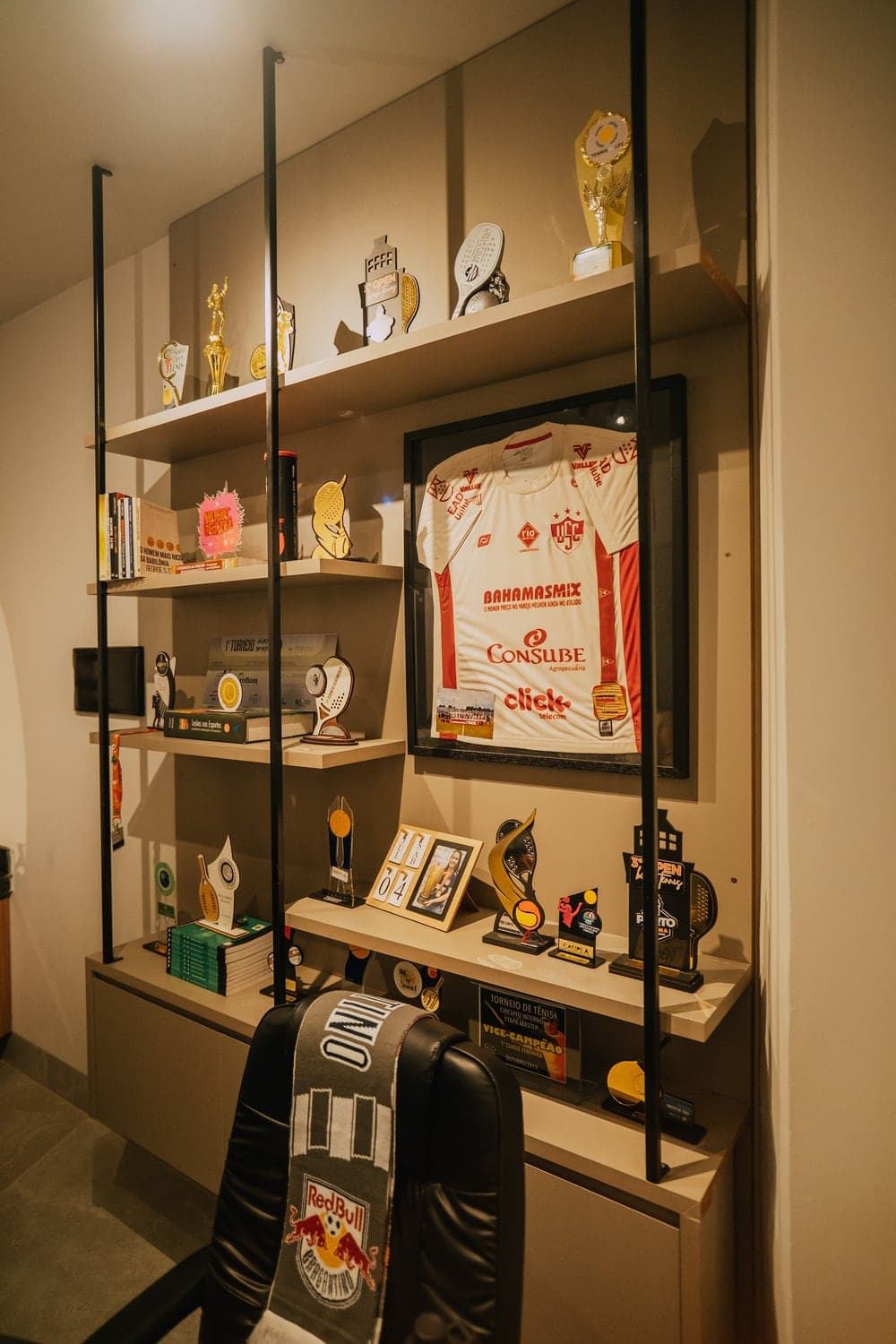 Estante de troféus, medalhas e uma camisa esportiva emoldurada no Via Move.